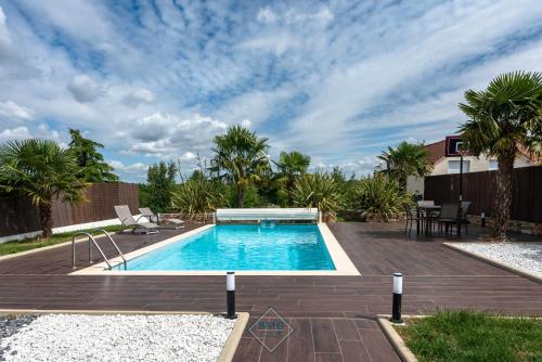 - une piscine dans un jardin avec une terrasse en bois dans l'établissement Luxury villa near Disneyland Bmyguest, à Gouvernes