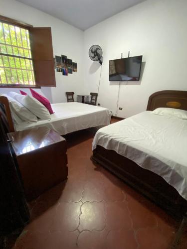 1 dormitorio con 2 camas y TV de pantalla plana en Habitacion Casa Campestre con piscina en Buga, 