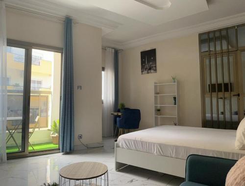 um quarto com uma cama, uma mesa e uma janela em Le doux refuge em Dakar