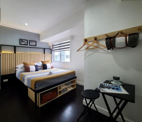 a bedroom with a bed and a table with a stool at BGC Central Comforts in Manila