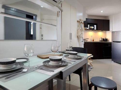 a kitchen with a table with plates and wine glasses at BGC Central Comforts in Manila