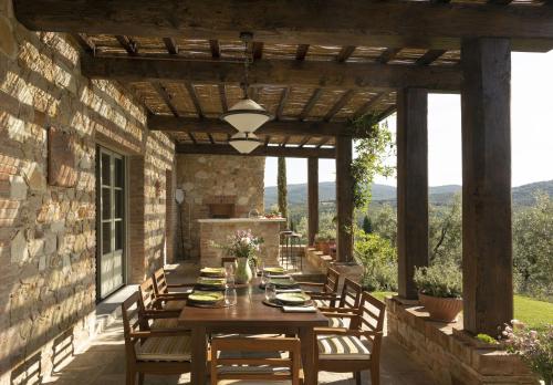 a patio with a table and chairs and a stone wall at Castello di Casole, A Belmond Hotel, Tuscany in Casole dʼElsa