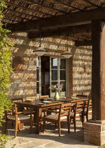a wooden table and chairs on a patio at Castello di Casole, A Belmond Hotel, Tuscany in Casole dʼElsa