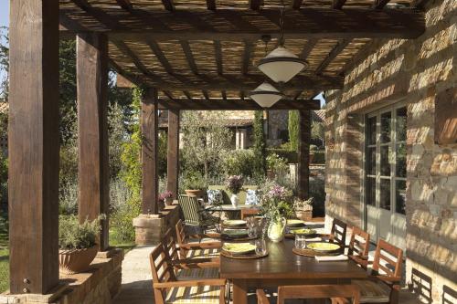 an outdoor dining area with a wooden pergola at Castello di Casole, A Belmond Hotel, Tuscany in Casole dʼElsa