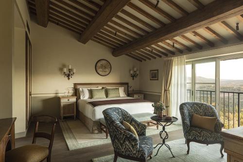 a bedroom with a bed and chairs and a balcony at Castello di Casole, A Belmond Hotel, Tuscany in Casole dʼElsa
