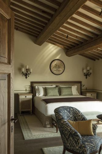 a bedroom with a large bed and a chair at Castello di Casole, A Belmond Hotel, Tuscany in Casole dʼElsa
