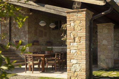 a patio with a table and chairs under a brick building at Castello di Casole, A Belmond Hotel, Tuscany in Casole dʼElsa