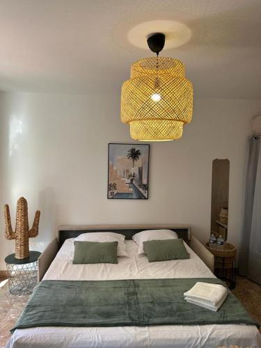 a bedroom with a large bed and a chandelier at Petit paradis Portissol 400m plage/commerces in Sanary-sur-Mer