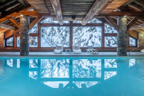 een zwembad met uitzicht op de met sneeuw bedekte bergen bij Résidence Pierre & Vacances Premium Les Fermes De Méribel in Méribel