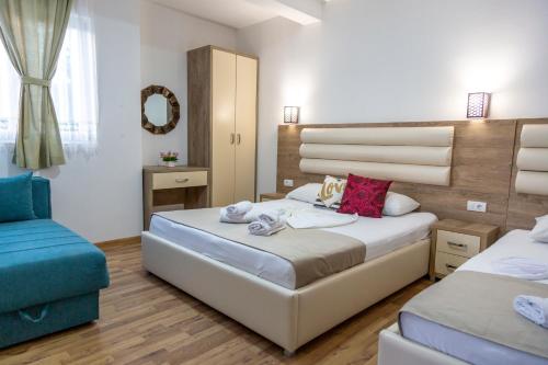 a bedroom with two beds and a blue chair at Kenzy Apartments in Ulcinj