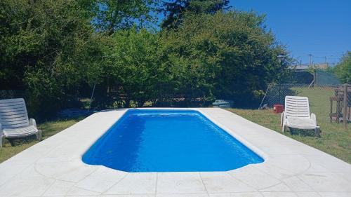 - une piscine bleue avec 2 chaises dans l'établissement La Obra, à Tandil