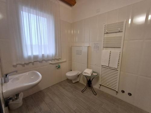 a white bathroom with a toilet and a sink at Arneroni in Codognè