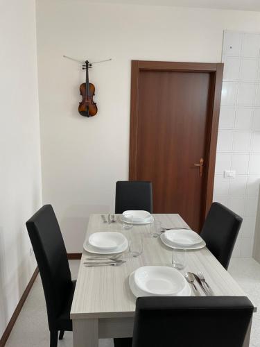 a wooden table with chairs and plates and a violin at House of music near venice in Mogliano Veneto
