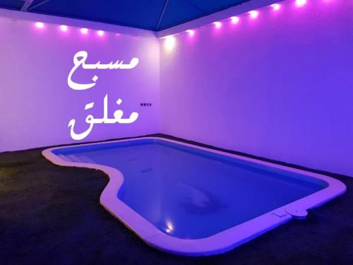 una camera con piscina con insegna al neon di شالية لايت مون a Dammam