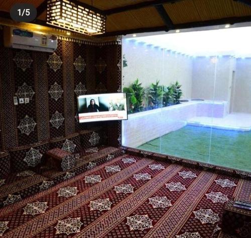 a room with a tv and a swimming pool at شالية لايت مون in Dammam