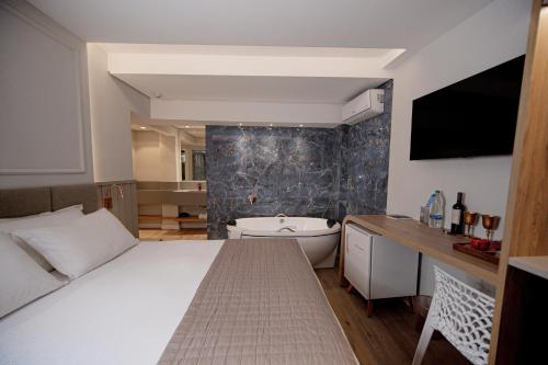 a bedroom with a bed and a bath tub and a television at Hotel Marimar The Place in Balneário Camboriú