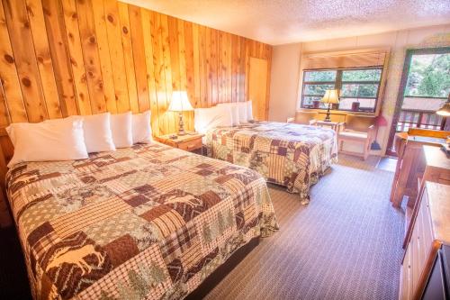 a hotel room with two beds and wooden walls at Castle Mountain Lodge in Estes Park