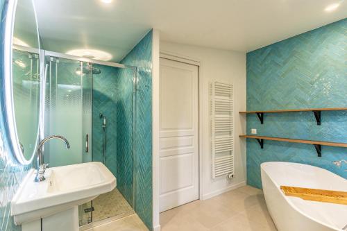 y baño con paredes de azulejos azules, bañera y lavamanos. en La Maison des Huîtres, en Arcachon