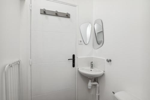 ein weißes Badezimmer mit einem Waschbecken und einem Spiegel in der Unterkunft Loft Paisible à Argenteuil / La défense/Beam in Argenteuil
