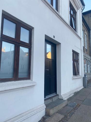 uma porta preta do lado de um edifício branco em En lille hel lejlighed i midtbyen - centralt, hyggelig og tæt på alt! em Randers