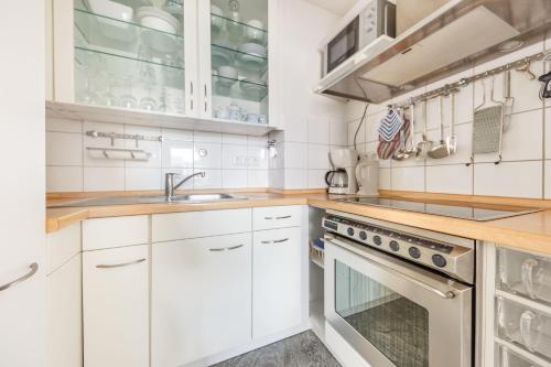 cocina con armarios blancos, fregadero y fogones en Haus-Momoa-Duenenburg, en Westerland