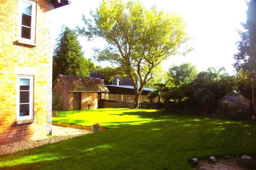 un patio con un árbol y una casa de ladrillo en Elm Cottage en Alvescot
