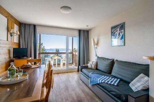 a living room with a couch and a dining room table at Résidence Pierre & Vacances Le Pédrou in Font-Romeu