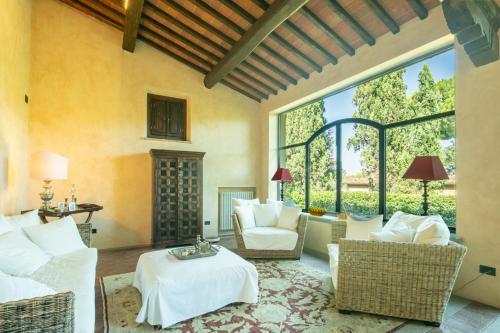 a living room with white furniture and a large window at Villa Belforte by VacaVilla in Lamporecchio