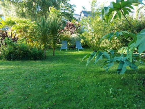 Deux chaises bleues dans une cour avec de l'herbe verte dans l'établissement Le Jardin de Wéléat, à Valognes