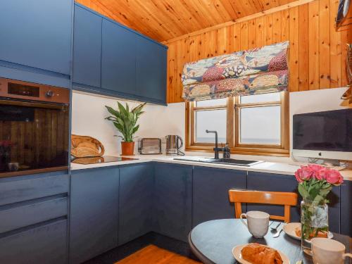 a kitchen with blue cabinets and a table and a sink at Kestrel in Seaton