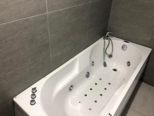 a white bath tub in a bathroom with a tile wall at OnLux sobe in Kragujevac