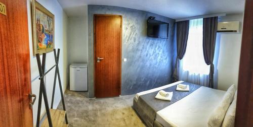 a room with a bed and a door with a television at OnLux sobe in Kragujevac