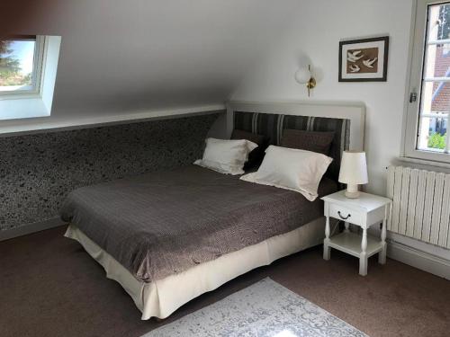 1 dormitorio con 1 cama y mesita de noche con lámpara en Le clos fleuri - Chambres d'hôtes en Onzain