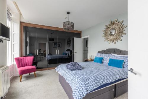 a bedroom with a bed and a pink chair at BEACH VIEW - Amazing Sea Views in Lytham St Annes