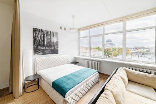 a bedroom with a bed and a couch and a window at Apartament 502 in Kaunas