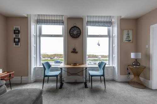 - un salon avec une table, des chaises et une horloge dans l'établissement BEACH VIEW - Amazing Sea Views, à Lytham St Annes