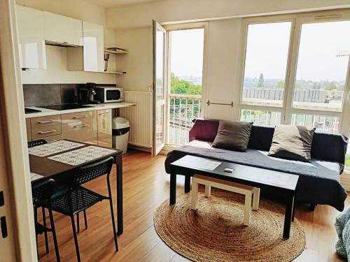 a living room with a couch and a table in a kitchen at Grand Studio Paris Le Bourget in Le Bourget