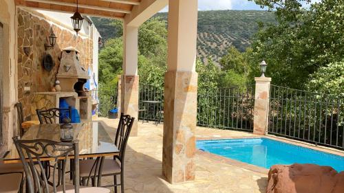 eine Terrasse mit einem Tisch und Stühlen neben einem Pool in der Unterkunft 5 bedrooms house with private pool furnished terrace and wifi at Zambra in Zambra