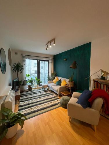 una sala de estar con 2 sofás y una pared verde en Cosy Modern Apartment in Portobello, en Dublín