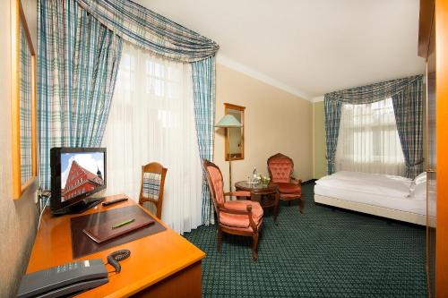 ein Hotelzimmer mit einem Schlafzimmer mit einem Bett und einem Schreibtisch in der Unterkunft Hotel Kronprinz in Greifswald
