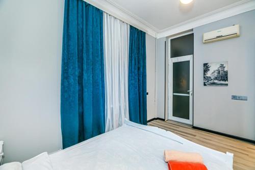 Schlafzimmer mit einem Bett mit blauen Vorhängen und einem Fenster in der Unterkunft Qız Qalası 2 room Sweet Home in Baku