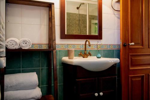 a bathroom with a sink and a mirror and towels at Casa Rural Pontevedra con piscinajardínbarbacoa in Pontevedra