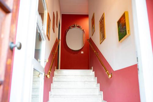 a hallway with red walls and white stairs with a mirror at La Corte di Aldo in Rozzano