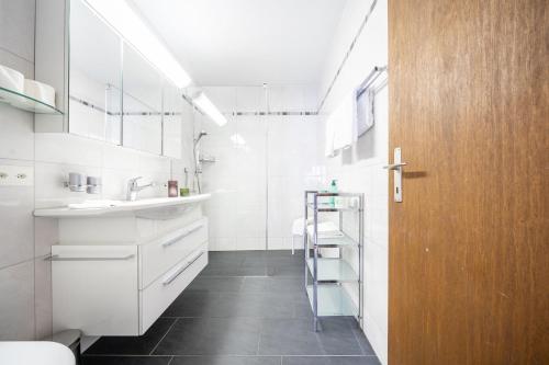 baño con armarios blancos y lavamanos en PL 204 Geraeumige 3,5-Zimmer-Wohnung im Haus Plavna mit grossem Balkon, en Vulpera