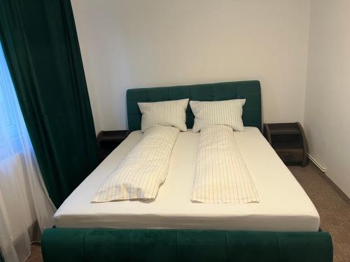 a bed with a green headboard and two pillows at Green Apartament in Bacău
