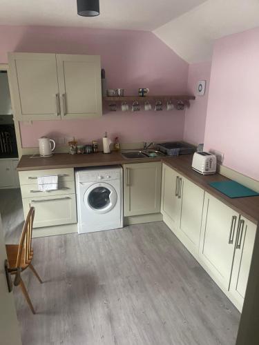 a kitchen with white cabinets and a washing machine at Ninian Park Road in Cardiff