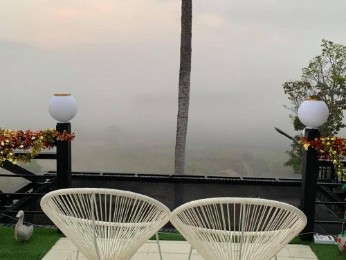 - deux chaises blanches assises sur le balcon dans l'établissement Elevated Serenity Lodge in Khao Kho, à Khao Kho