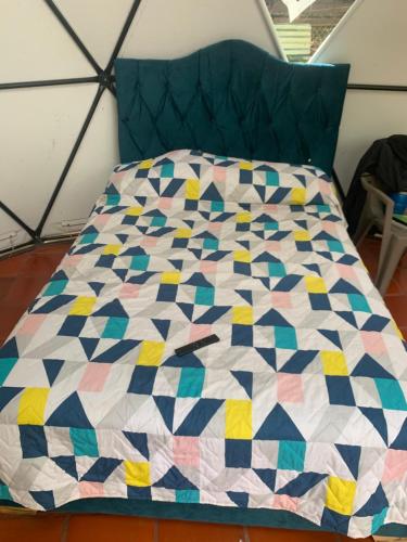 a bed with a colorful quilt on it at Hotel Ambrosia Lodge in Rivera