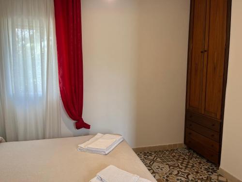 a bedroom with a bed and a window with red curtains at Casette Masseria La Camardia in Sava