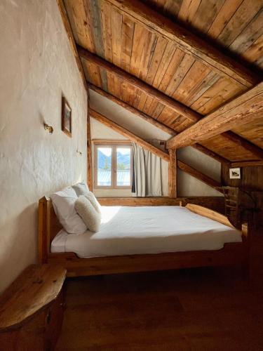 un lit dans une chambre avec un plafond en bois dans l'établissement Chalet typique accueillant jusqu'à 9 personnes, à Champagny-en-Vanoise